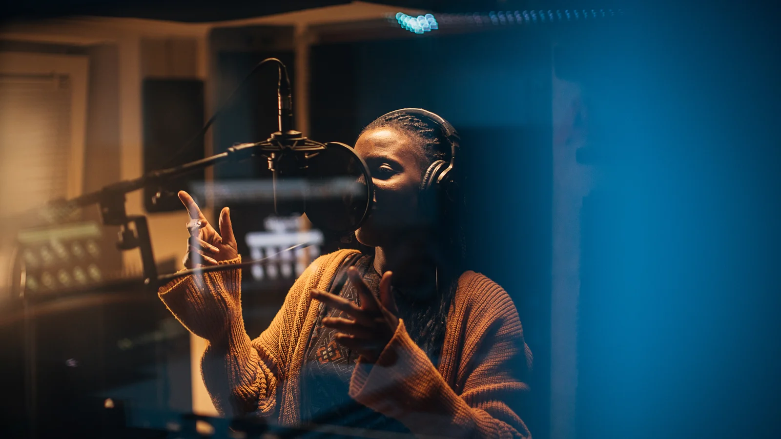 Kvinna står med hörlurar och sjunger in i en mikrofon i musikstudio